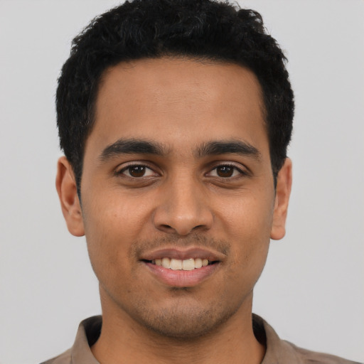 Joyful latino young-adult male with short  black hair and brown eyes