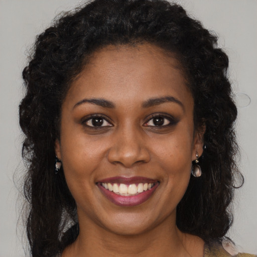 Joyful black young-adult female with long  brown hair and brown eyes