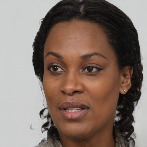 Joyful black adult female with long  brown hair and brown eyes