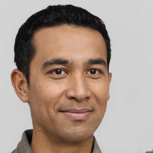 Joyful latino young-adult male with short  black hair and brown eyes