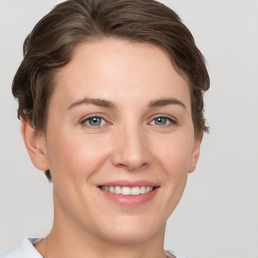 Joyful white young-adult female with short  brown hair and grey eyes