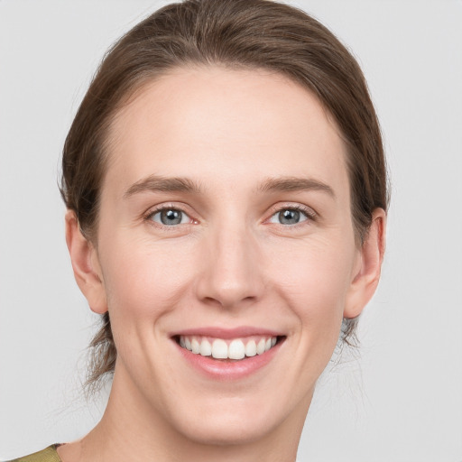 Joyful white young-adult female with medium  brown hair and grey eyes