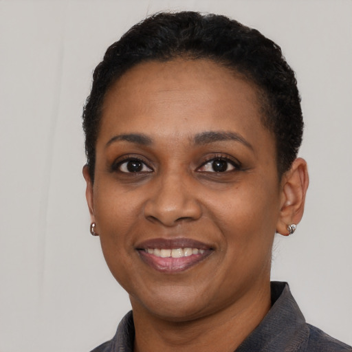 Joyful black young-adult female with short  black hair and brown eyes