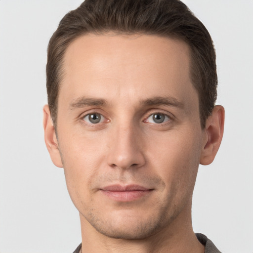 Joyful white young-adult male with short  brown hair and grey eyes