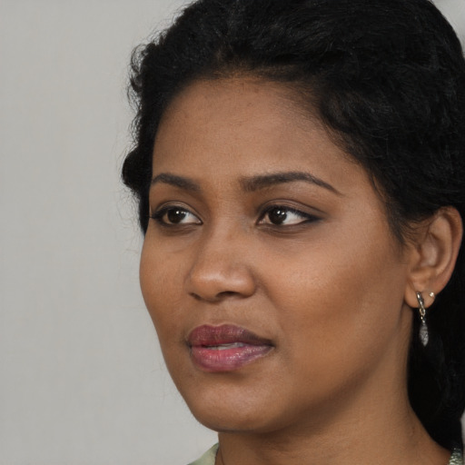 Joyful black young-adult female with long  brown hair and brown eyes