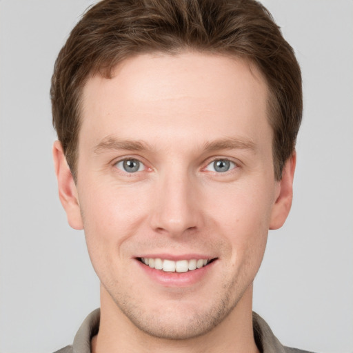 Joyful white young-adult male with short  brown hair and grey eyes