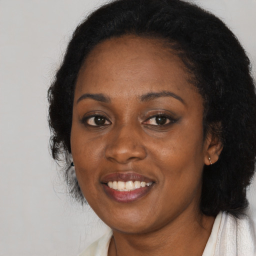 Joyful black young-adult female with long  black hair and brown eyes