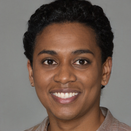 Joyful black young-adult female with short  black hair and brown eyes