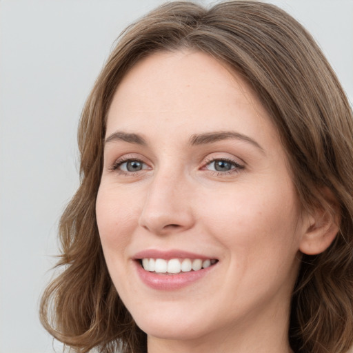 Joyful white young-adult female with long  brown hair and blue eyes