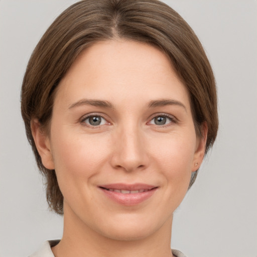 Joyful white young-adult female with medium  brown hair and grey eyes