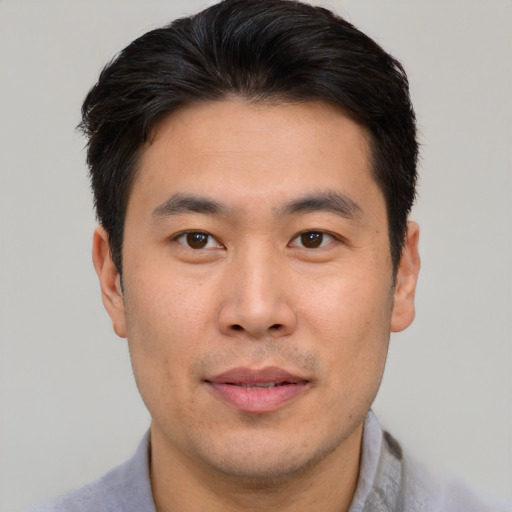Joyful asian young-adult male with short  brown hair and brown eyes
