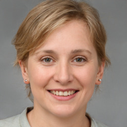 Joyful white young-adult female with medium  brown hair and grey eyes