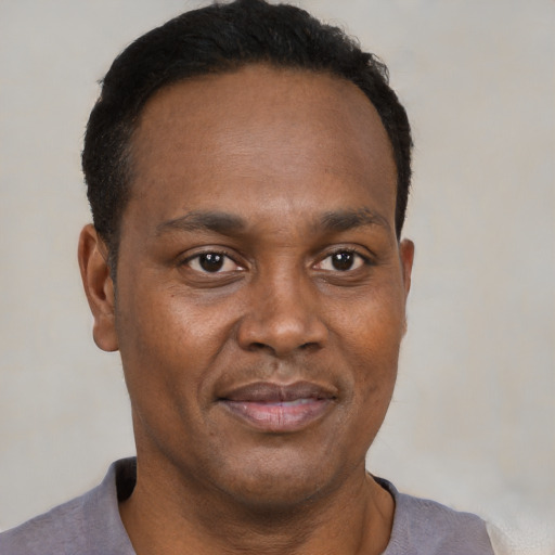 Joyful black young-adult male with short  black hair and brown eyes