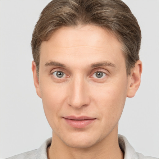 Joyful white young-adult male with short  brown hair and grey eyes