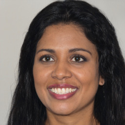 Joyful black young-adult female with long  brown hair and brown eyes