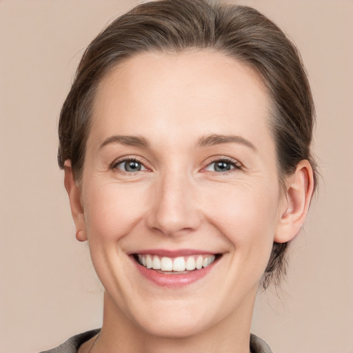 Joyful white young-adult female with medium  brown hair and grey eyes