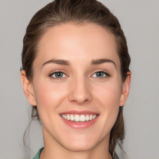 Joyful white young-adult female with medium  brown hair and grey eyes