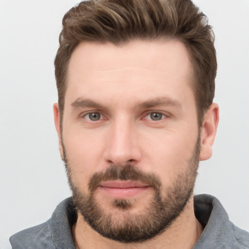 Joyful white young-adult male with short  brown hair and grey eyes