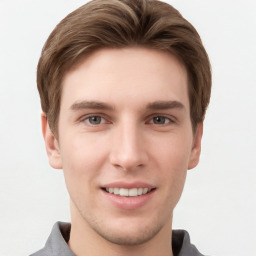 Joyful white young-adult male with short  brown hair and grey eyes