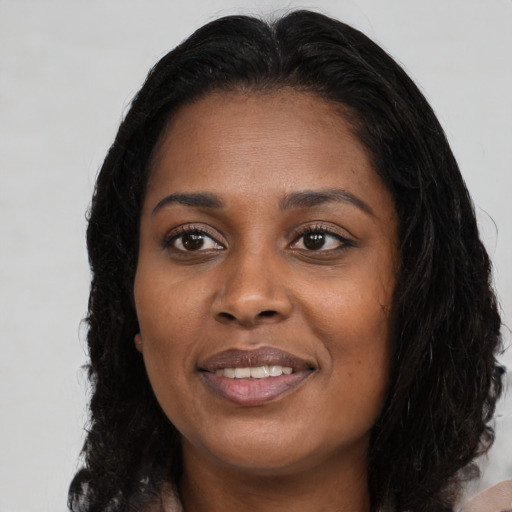 Joyful black young-adult female with long  brown hair and brown eyes