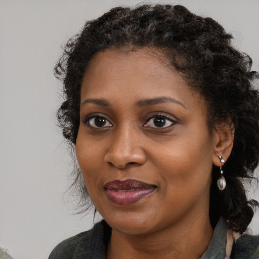 Joyful black young-adult female with long  brown hair and brown eyes