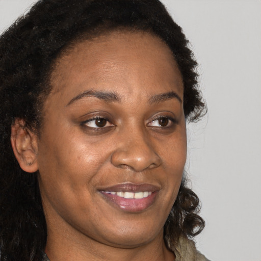 Joyful black young-adult female with long  brown hair and brown eyes