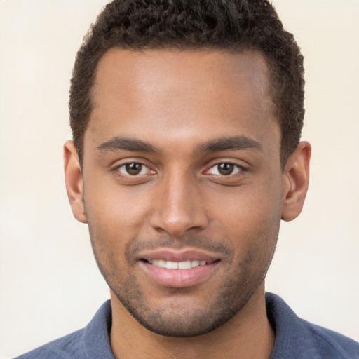 Joyful black young-adult male with short  brown hair and brown eyes