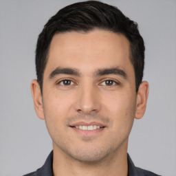 Joyful white young-adult male with short  black hair and brown eyes