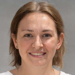 Joyful white young-adult female with medium  brown hair and grey eyes