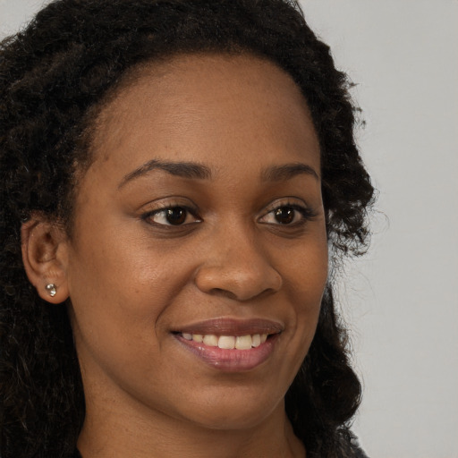 Joyful black young-adult female with long  brown hair and brown eyes