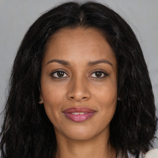 Joyful black young-adult female with long  brown hair and brown eyes