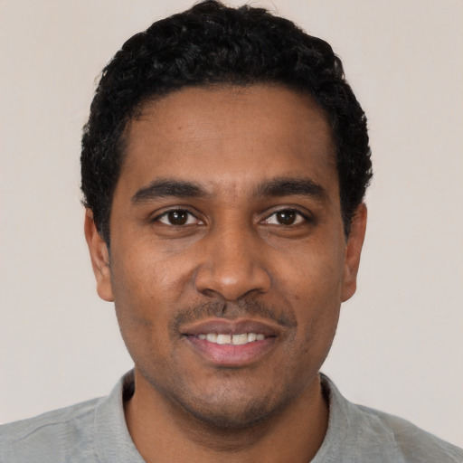 Joyful black young-adult male with short  black hair and brown eyes
