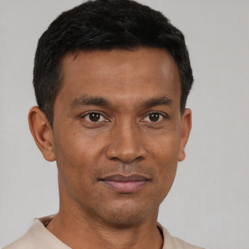 Joyful black young-adult male with short  black hair and brown eyes
