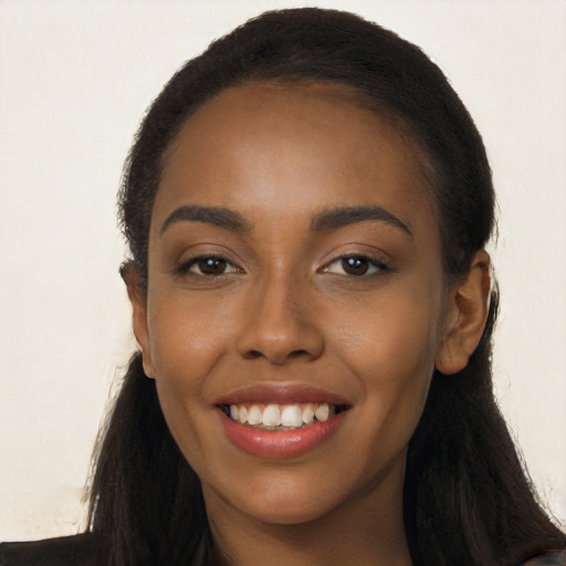 Joyful black young-adult female with long  black hair and brown eyes