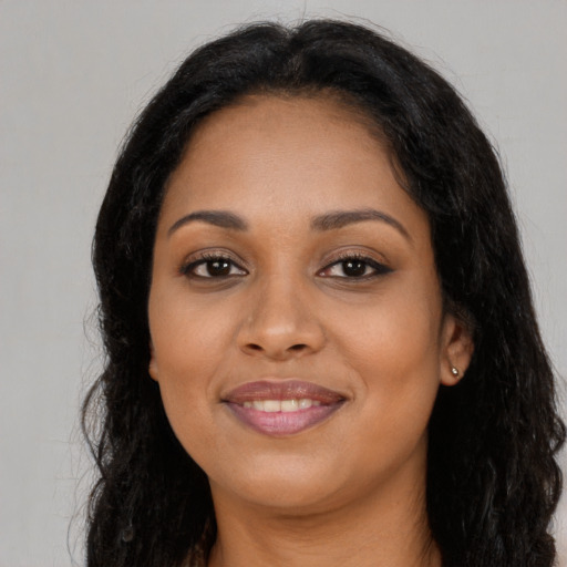 Joyful black young-adult female with long  brown hair and brown eyes