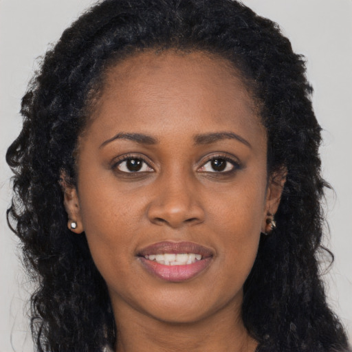 Joyful black young-adult female with long  brown hair and brown eyes