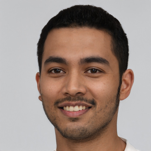 Joyful latino young-adult male with short  black hair and brown eyes