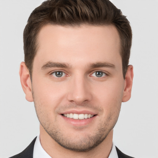 Joyful white young-adult male with short  brown hair and grey eyes