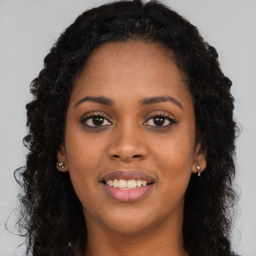 Joyful black young-adult female with long  black hair and brown eyes
