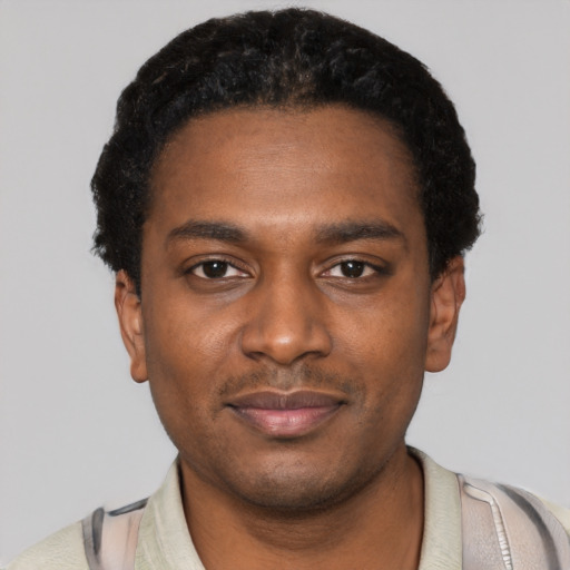 Joyful black young-adult male with short  black hair and brown eyes