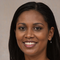 Joyful black young-adult female with long  brown hair and brown eyes