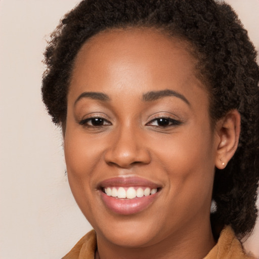 Joyful black young-adult female with long  brown hair and brown eyes