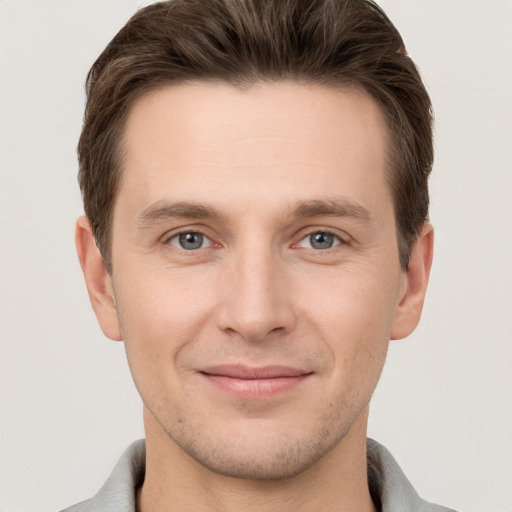 Joyful white young-adult male with short  brown hair and grey eyes