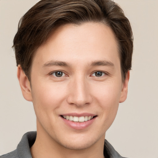 Joyful white young-adult male with short  brown hair and grey eyes