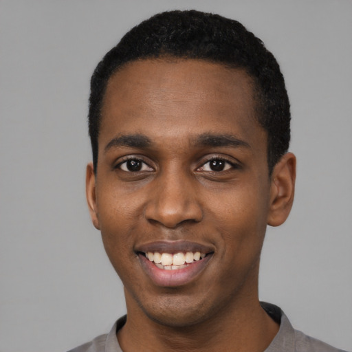Joyful black young-adult male with short  black hair and brown eyes