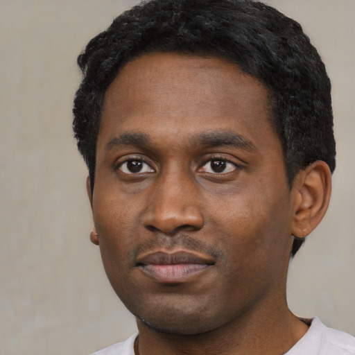 Joyful black young-adult male with short  black hair and brown eyes