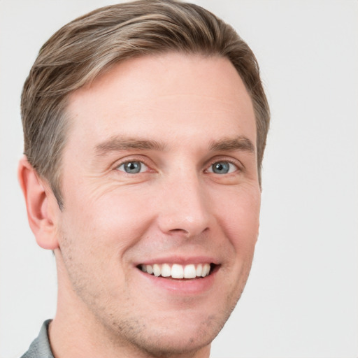 Joyful white young-adult male with short  brown hair and grey eyes