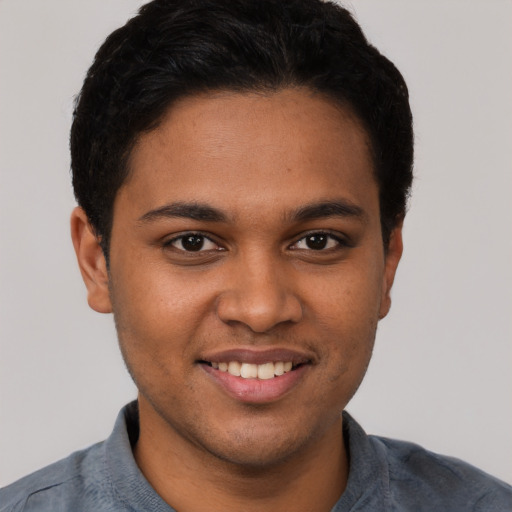 Joyful black young-adult male with short  brown hair and brown eyes