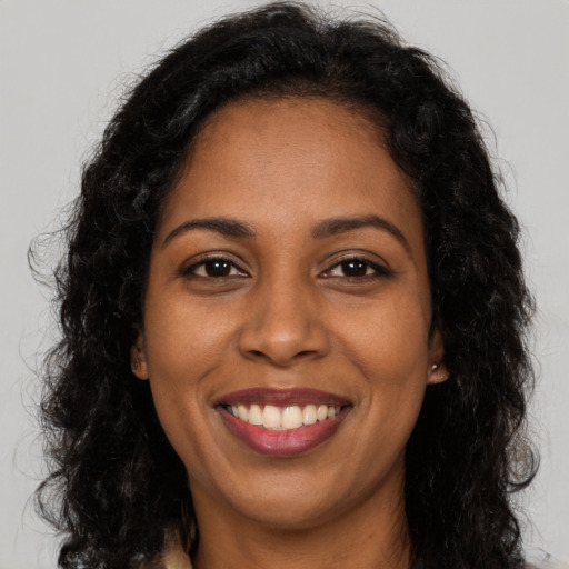 Joyful black adult female with long  brown hair and brown eyes