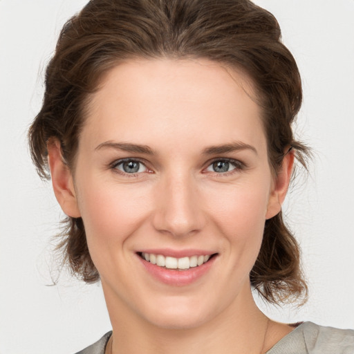 Joyful white young-adult female with medium  brown hair and grey eyes